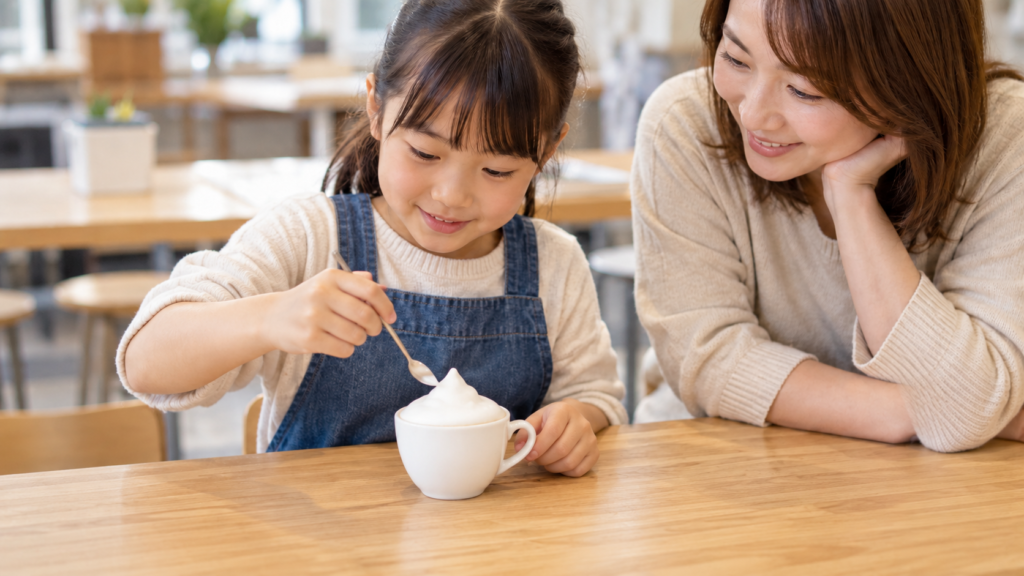 保護者が見守る中でミルクの泡の作品を作る子どもの手元