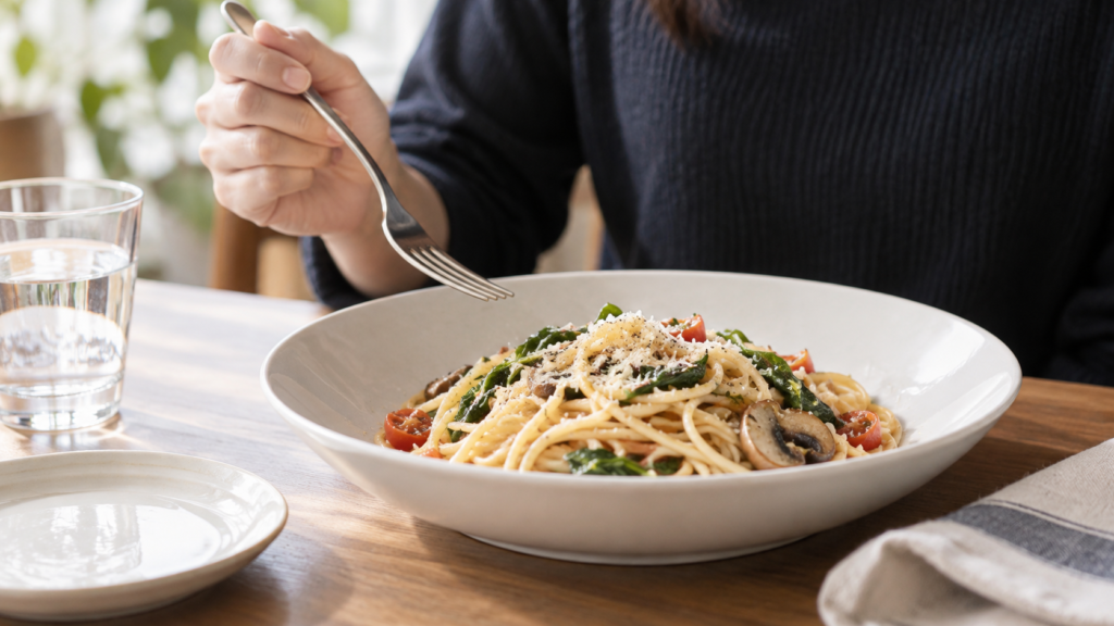 無地の器のパスタとフォークを前に食事量を考える説明用イメージ